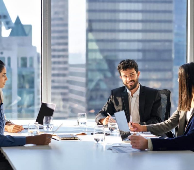Happy international multiethnic professional business team, diverse executive colleagues people discussing financial project working together in office at group meeting table in corporate board room.